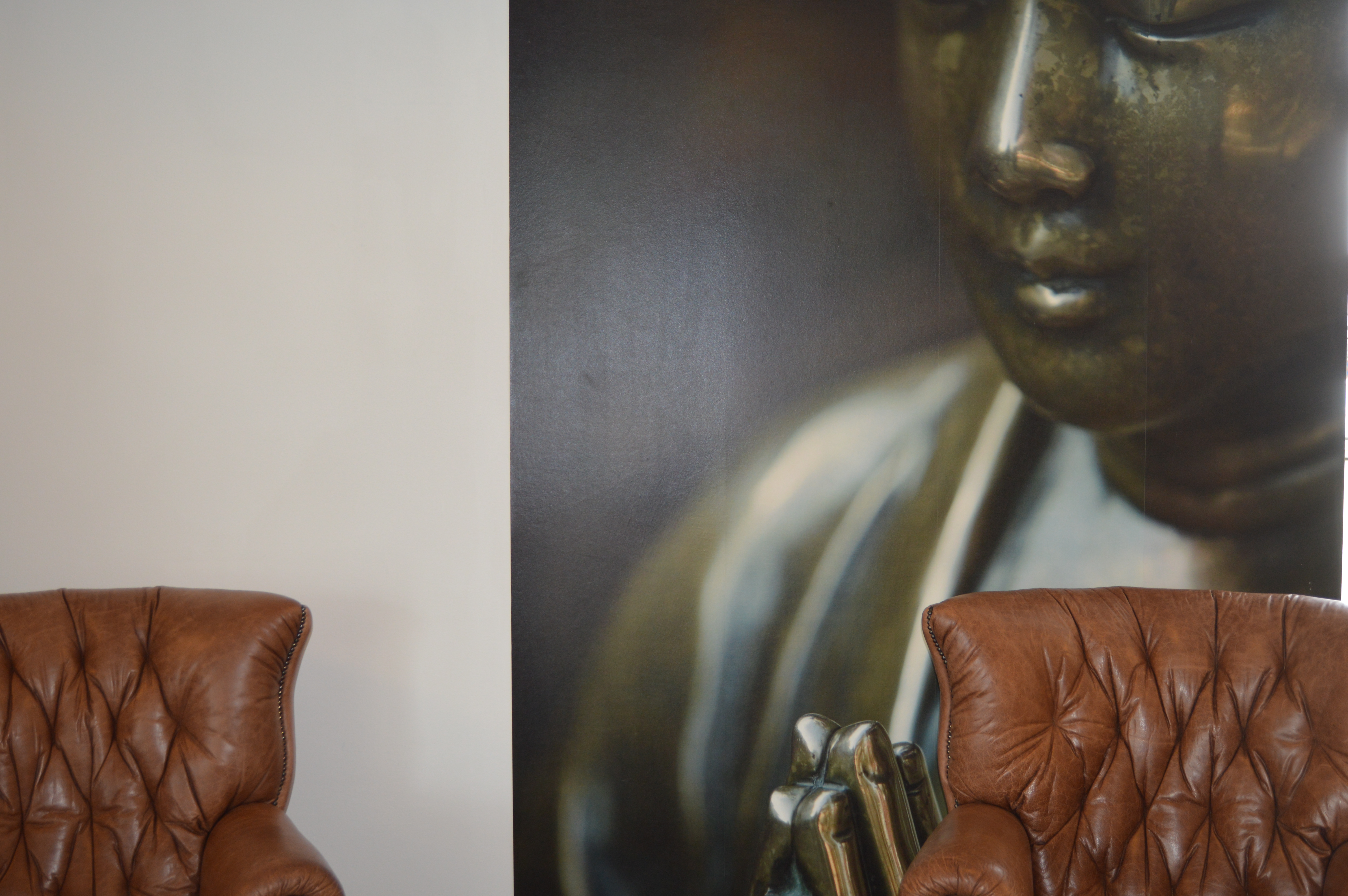 Klinikkens indretning — læderchesterfield stole foran Buddha-motiv